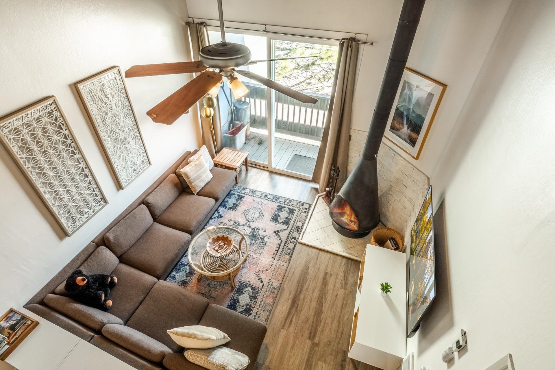 137 Laurel Mountain Road, Unit 227 Mammoth Lakes, CA 93546 - Photo 1 of 17 Living area featuring wood finished floors, a wood stove, a ceiling fan, and a high ceiling