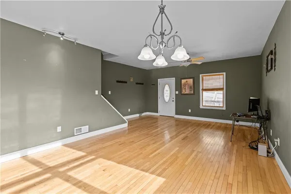 a kitchen with stainless steel appliances kitchen island granite countertop a refrigerator a stove a sink and white cabinets with wooden floor