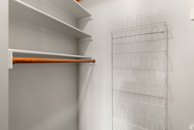 435 Canyon Road Millville, UT 84326 - Photo 19 of 113 Closet interior featuring a wooden hanging rod, white shelving, and a wall-mounted wire shoe rack