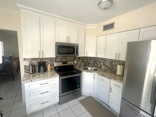 a kitchen with granite countertop a refrigerator stove and sink