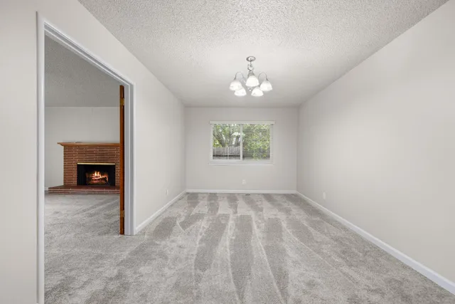 an empty room with windows chandelier and fireplace