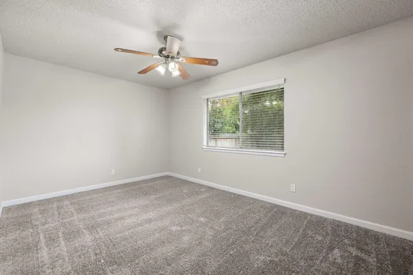 an empty room with a window and a fan
