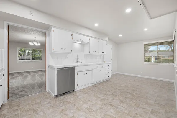 a large white kitchen with kitchen island a sink stainless steel appliances and cabinets