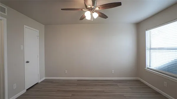 a view of an empty room with wooden floor and a window
