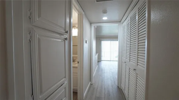 a view of a hallway with wooden floor and closet area