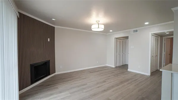 an empty room with wooden floor fireplace and staircase