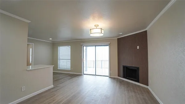 an empty room with wooden floor fireplace and windows