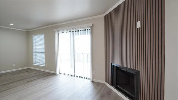 a view of an empty room with wooden floor and a fireplace