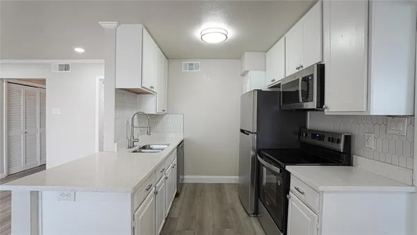 a kitchen with stainless steel appliances a sink stove refrigerator and cabinets