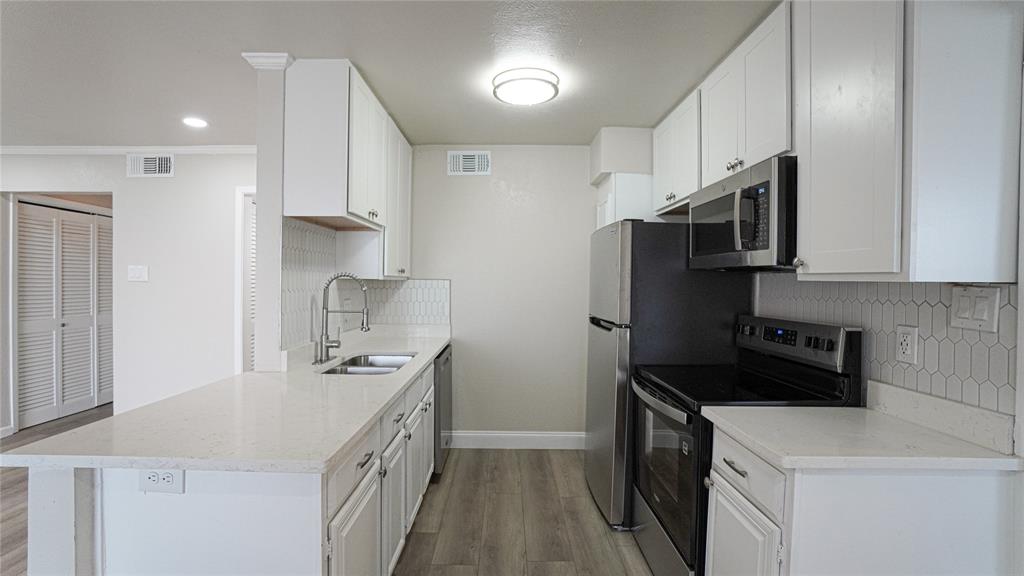 4606 Chaha Road, Unit 103 Garland, TX 75043 - Photo 8 of 23 a kitchen with stainless steel appliances a sink stove refrigerator and cabinets