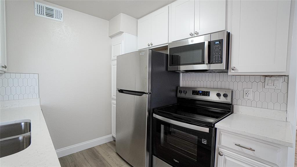 4606 Chaha Road, Unit 103 Garland, TX 75043 - Photo 9 of 23 a kitchen with stainless steel appliances a stove microwave and refrigerator