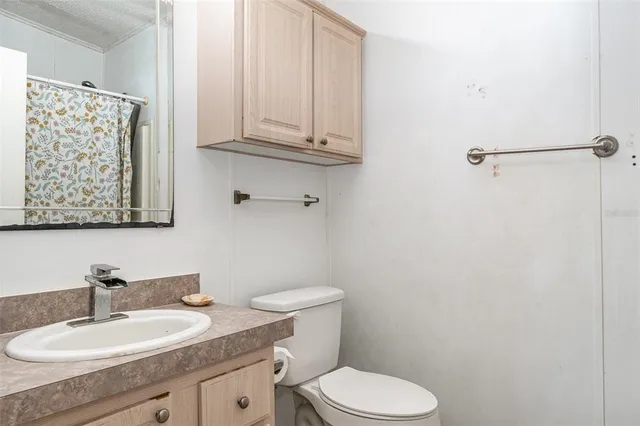 a bathroom with a granite countertop toilet sink and mirror