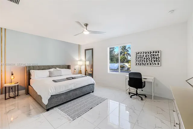 a bedroom with a bed a table chair and a window