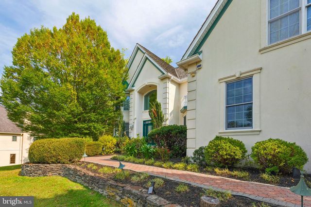 a front view of a house with a garden and trees