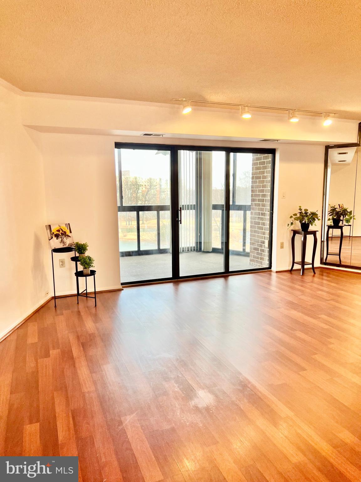 15115 Interlachen Drive, Unit 3603 Silver Spring, MD 20906 - Photo 13 of 49 a view of an empty room with window and wooden floor