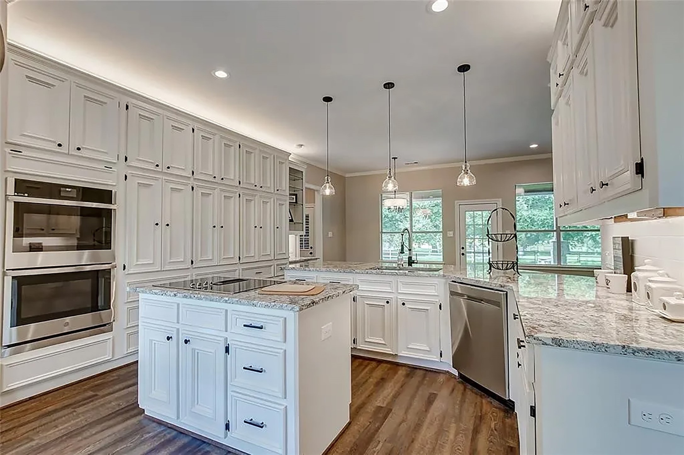 4421 Bowser Road Fulshear, TX 77441 - Photo 6 of 41 a kitchen with stainless steel appliances granite countertop a stove a sink and white cabinets with wooden floor