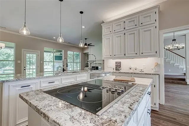 a kitchen with kitchen island granite countertop a sink a stove and wooden floors
