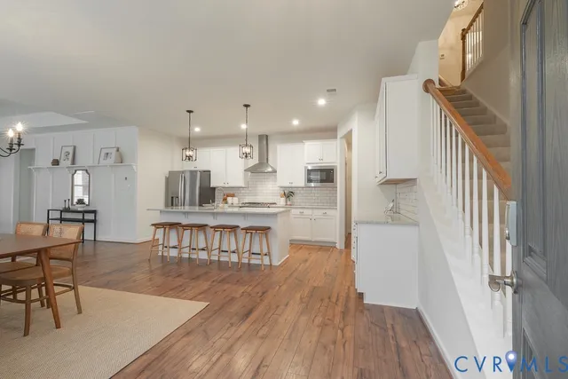 a living room with stainless steel appliances furniture and a wooden floor