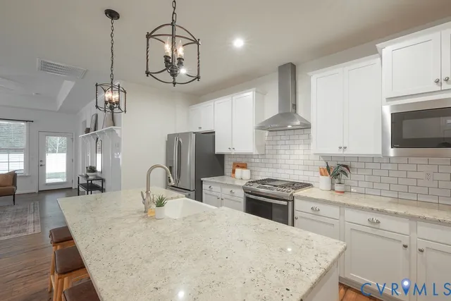 a kitchen with stainless steel appliances granite countertop a sink a stove oven a counter space a refrigerator and cabinets