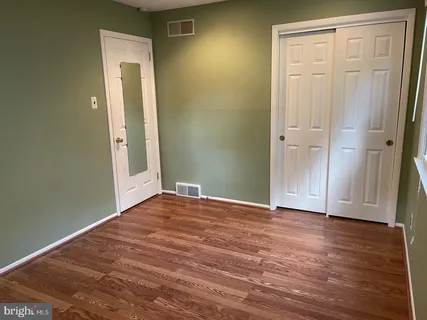 an empty room with wooden floor and closet