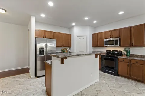 a kitchen with granite countertop a refrigerator and a stove top oven