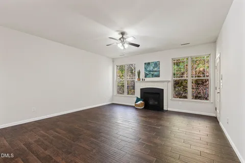 an empty room with fireplace wooden floor and windows