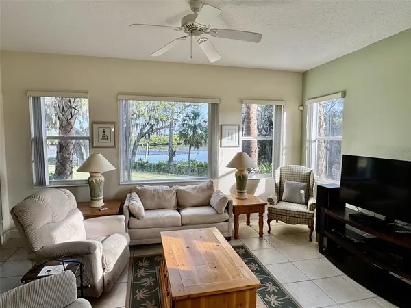 a living room with furniture a flat screen tv and a floor to ceiling window