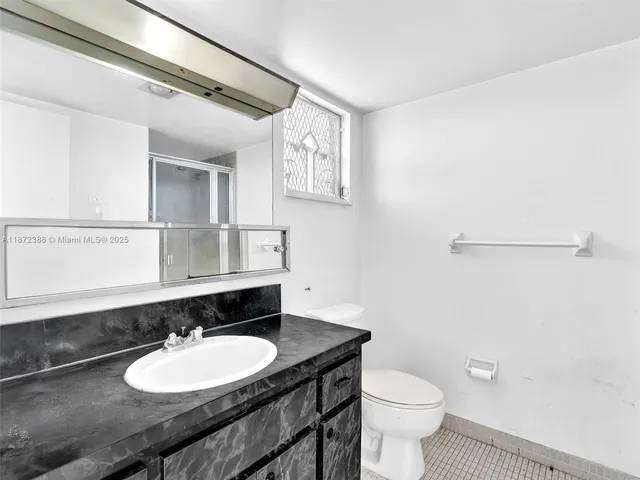 a bathroom with a granite countertop sink a toilet a mirror and shower