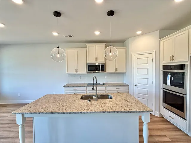 a kitchen with kitchen island granite countertop a sink and stainless steel appliances