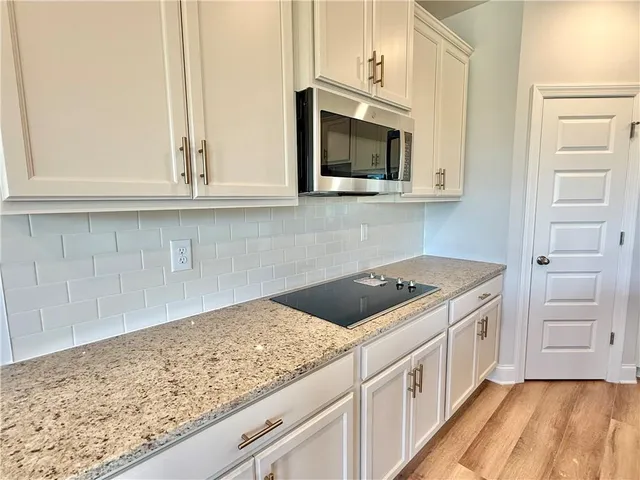 a kitchen with stainless steel appliances granite countertop white cabinets and a stove