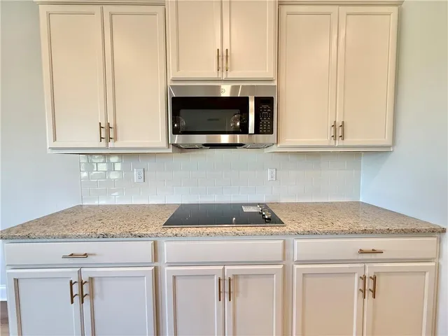 a kitchen with granite countertop white cabinets and a stove
