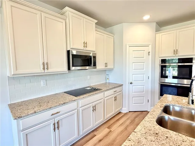 a kitchen with stainless steel appliances granite countertop a sink stove and cabinets