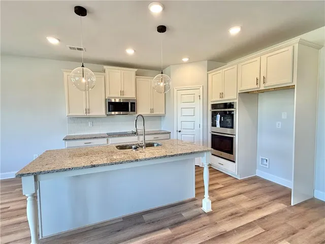 a large kitchen with stainless steel appliances granite countertop a sink a stove and a refrigerator