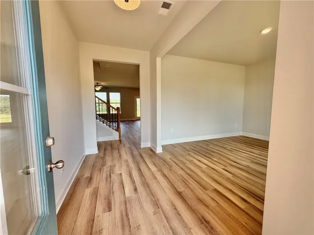 a view of a hallway with wooden floor and a bathroom