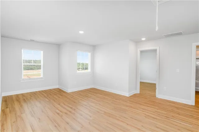 a view of empty room with wooden floor and fan