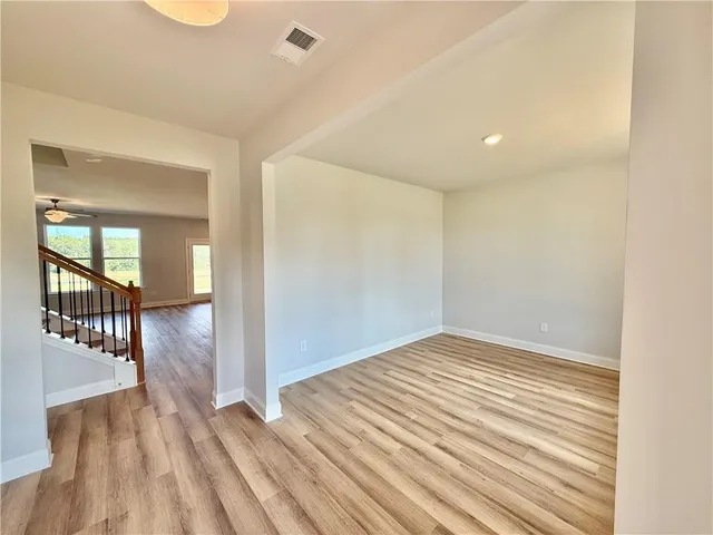 a view of a hallway with wooden floor and a bathroom