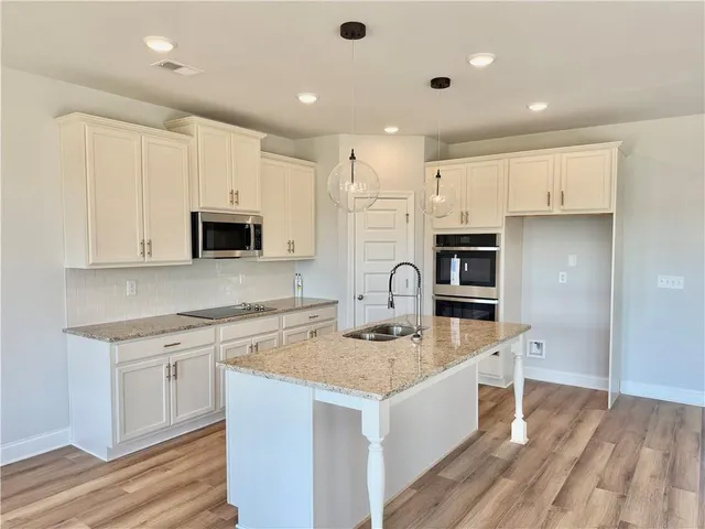 a kitchen with stainless steel appliances granite countertop a white cabinets a sink a stove a refrigerator and white cabinets
