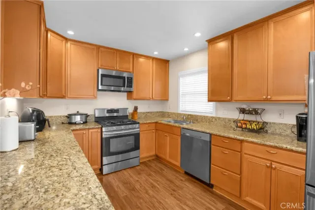 a kitchen with granite countertop wooden cabinets stainless steel appliances and a window