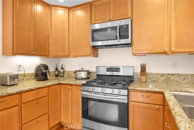 a kitchen with stainless steel appliances granite countertop a stove a sink and a microwave