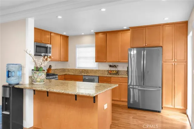 a kitchen with stainless steel appliances granite countertop a refrigerator a sink a stove a washer dryer and white cabinets