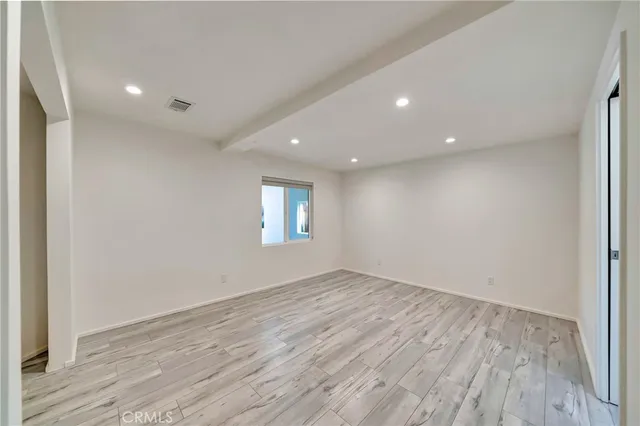 a view of an empty room with a window and wooden floor