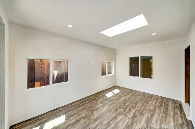 a living room with furniture and kitchen view with wooden floor