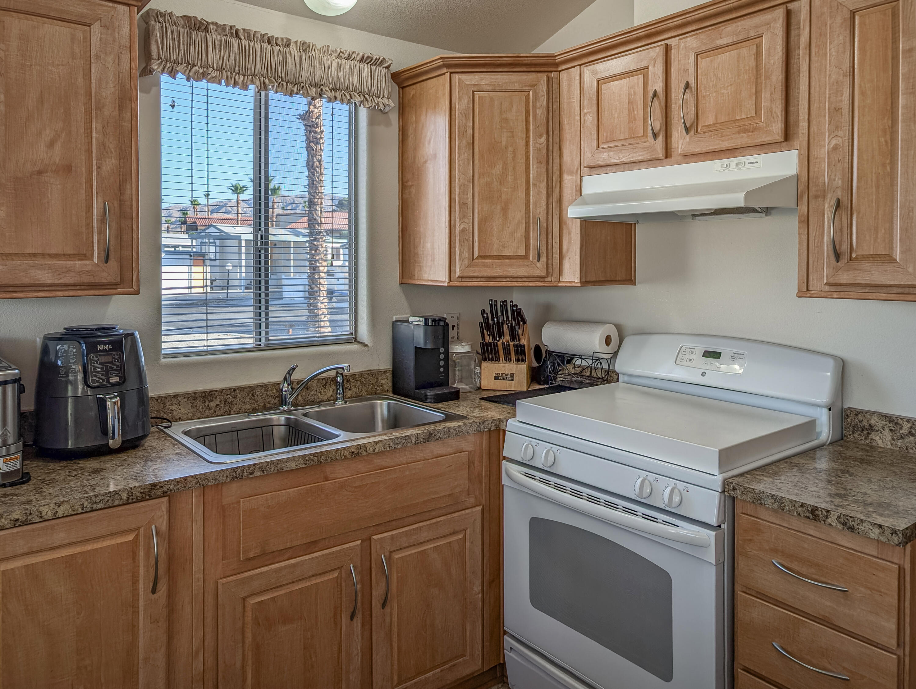 70200 Dillon Road, Unit 350 Desert Hot Springs, CA 92241 - Photo 11 of 22 a kitchen with granite countertop a sink a stove and cabinets