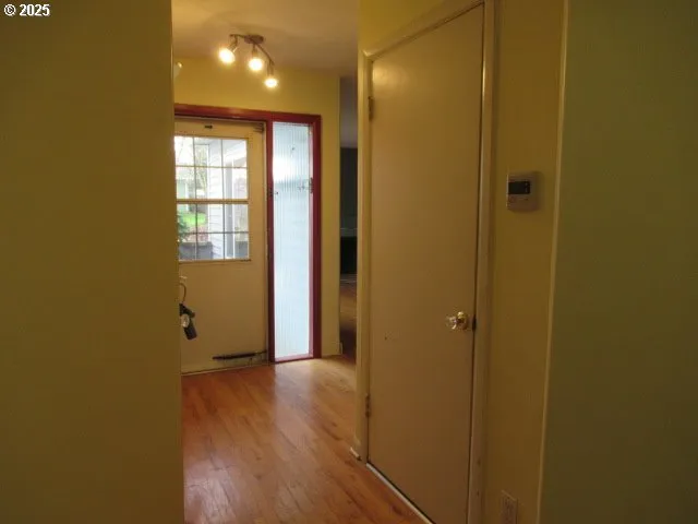 a view of a hallway with wooden floor and a bathroom