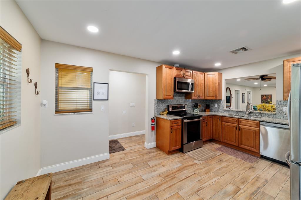16520 Northwest 170th Street Williston, FL 32696 - Photo 22 of 98 a kitchen with stainless steel appliances granite countertop a stove top oven a sink dishwasher a dining table and chairs with wooden floor
