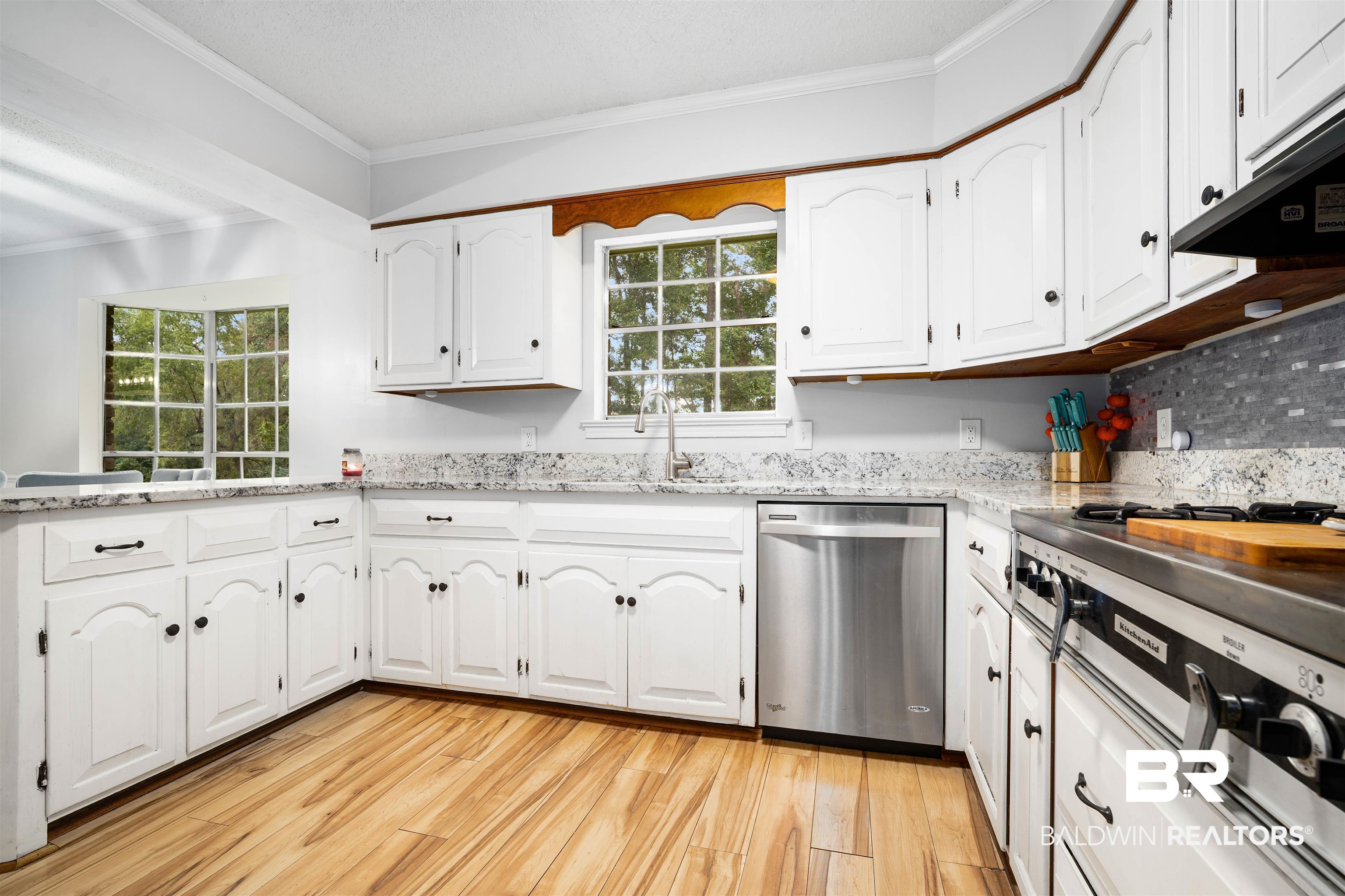 7807 Yorkhaven Road Mobile, AL 36695 - Photo 8 of 34 Kitchen featuring ornamental molding, light stone counters, appliances with stainless steel finishes, white cabinets, and light wood-type flooring