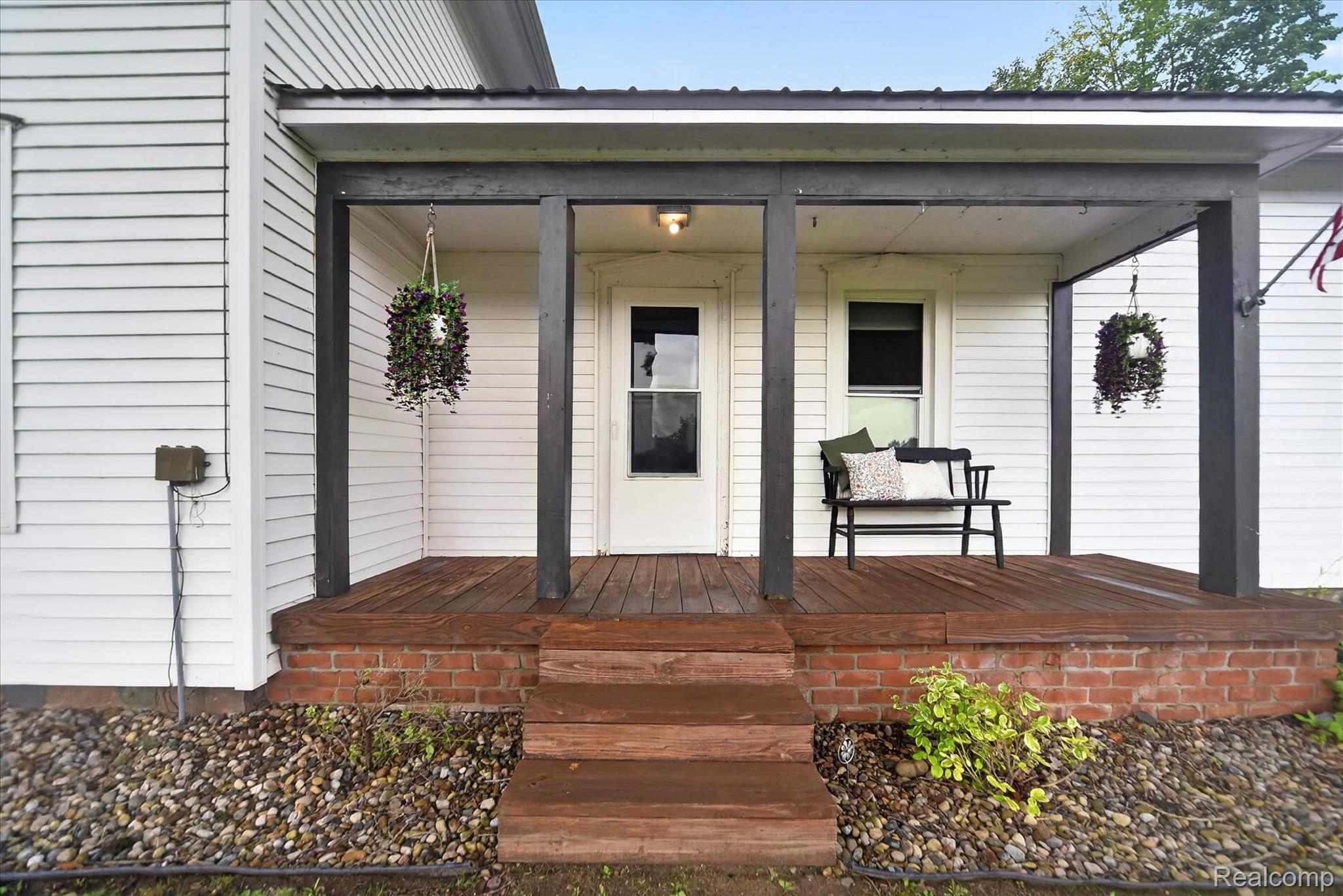 Covered porch featuring dark wood pillars and a wood-finish deck