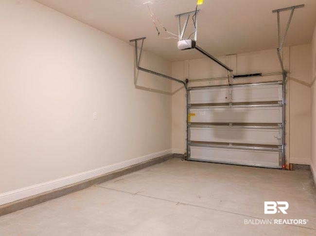 16810 Rocher Court Foley, AL 36535 - Photo 22 of 24 Spacious garage featuring a concrete floor, light-toned painted walls, white baseboards, and an overhead garage door opener system