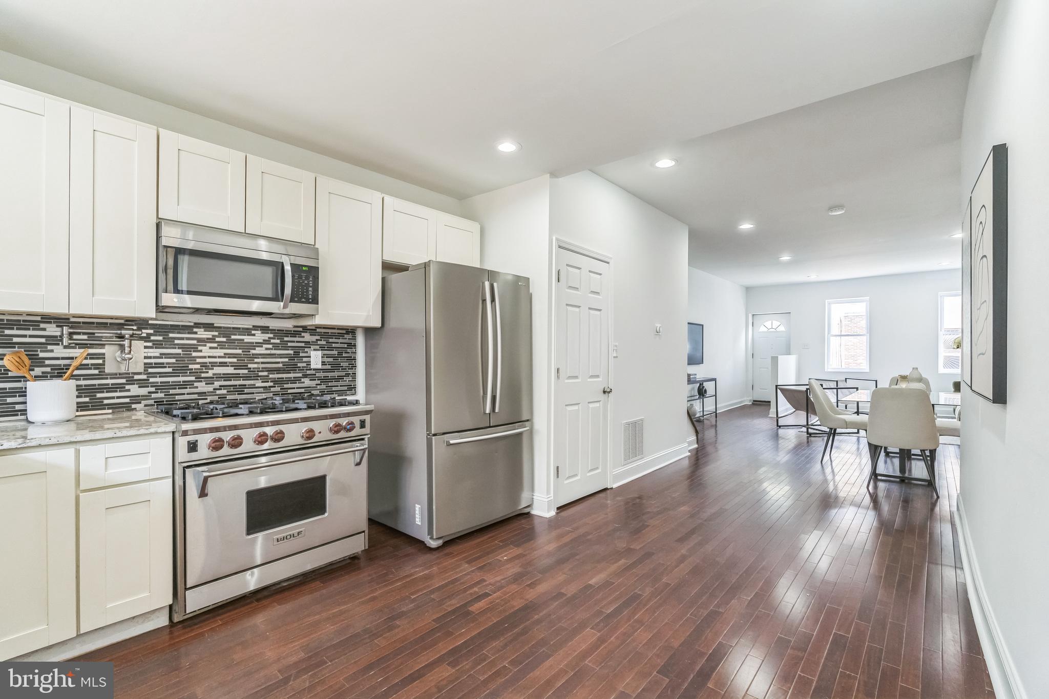 1816 Reed Street Philadelphia, PA 19146 - Photo 12 of 30 a kitchen with stainless steel appliances a stove a refrigerator cabinets and wooden floor