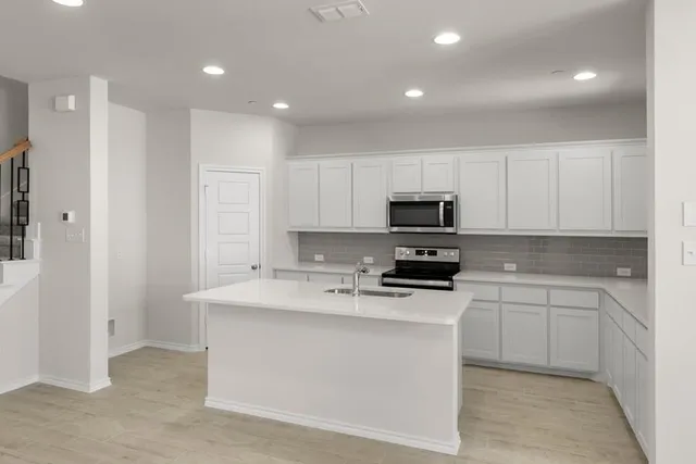 a kitchen with a sink a stove and cabinets